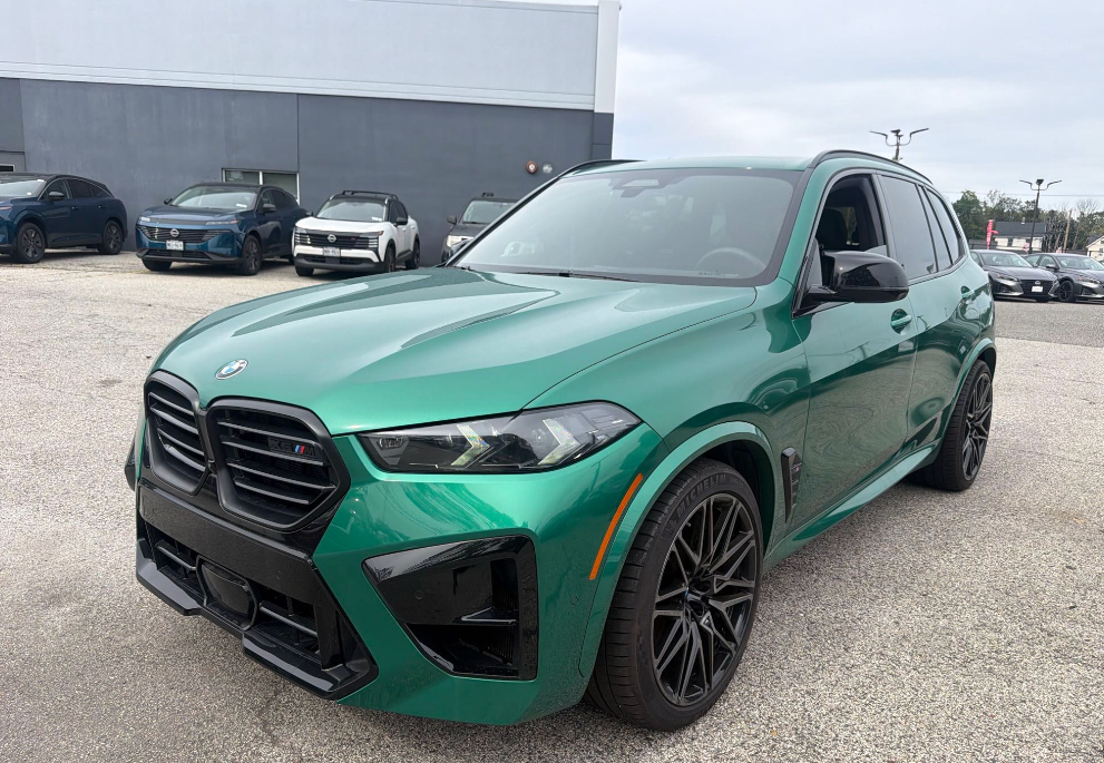 Isle of Man Green BMW X5 M SUV with a gloss black grille staged for transport on a service lot