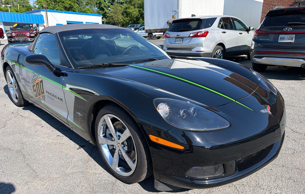 Black 2008 Chevrolet Corvette C6 Indianapolis 500 Pace Car replica convertible with pace car graphics on a dealership lot before Allstar Hauling transport