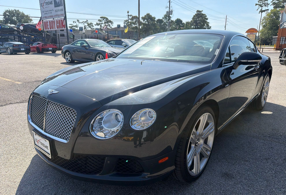 Dark gray Bentley Continental GT coupe on a dealer lot transported by Allstar Hauling