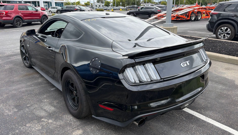 Black Ford Mustang GT twin-turbo 1,000hp coupe with drag radial tires and tri-bar taillights parked in front of an Allstar Hauling car carrier
