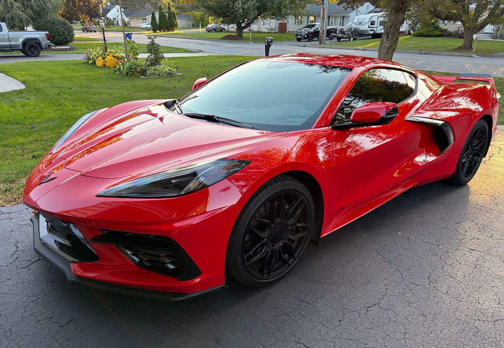 Torch Red Chevrolet Corvette C8 Stingray coupe with black mesh wheels parked in a driveway before Allstar Hauling transport
