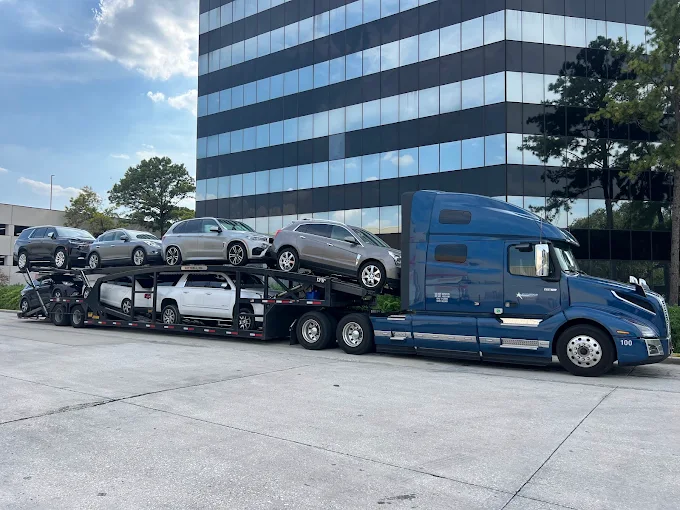 Blue Allstar Hauling Volvo VNL car carrier loaded with SUVs outside a corporate office building