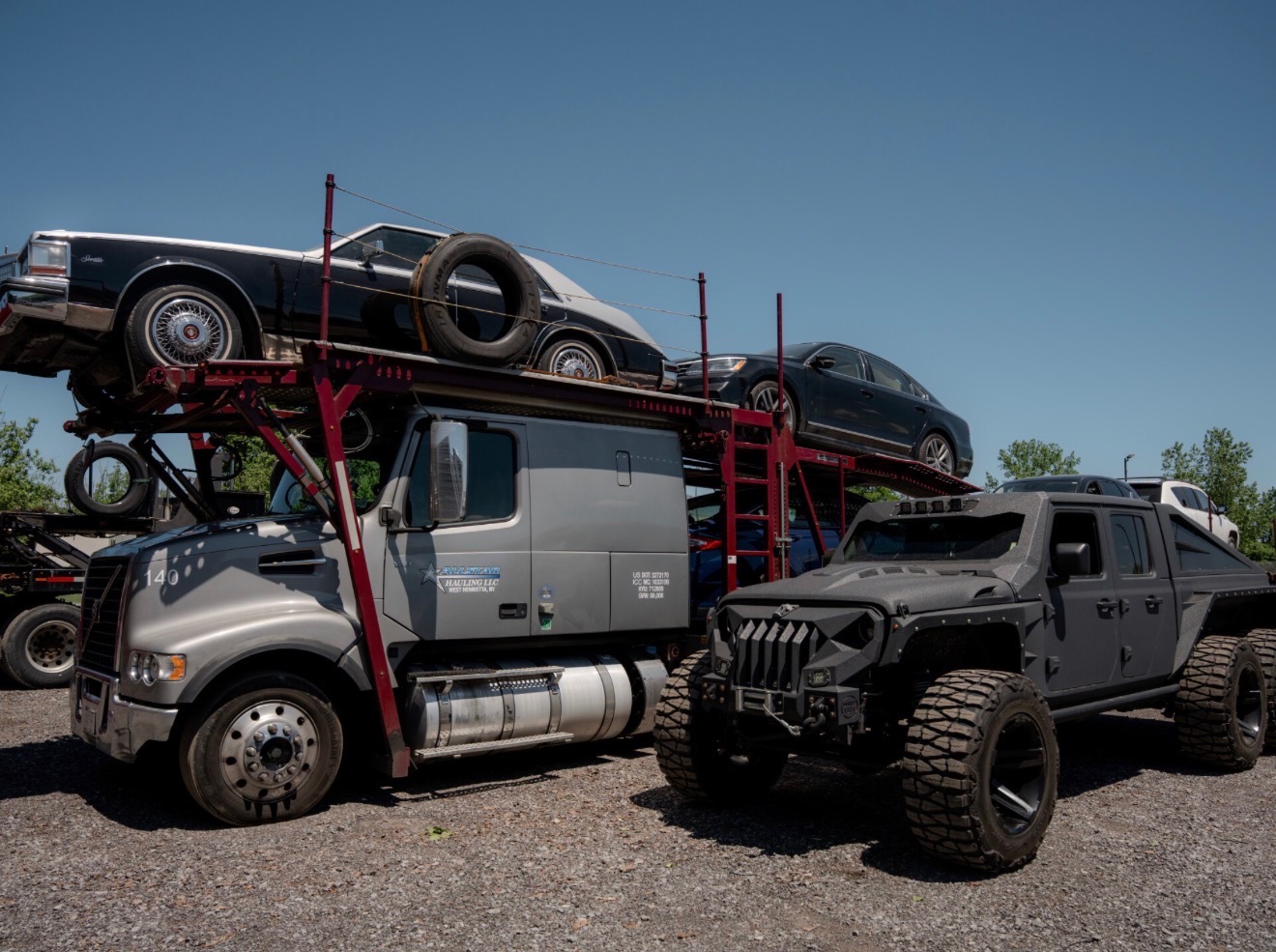 Custom matte black Jeep Gladiator six-wheeler next to an Allstar Hauling truck