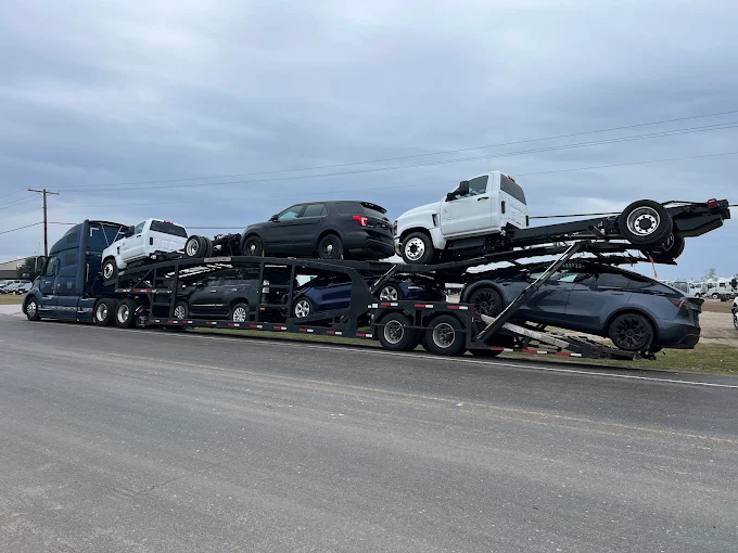 Allstar Hauling Volvo VNL car carrier loaded with heavy-duty trucks, an SUV and a Tesla